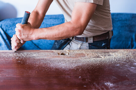 Man carrying out a stripping of the varnish of a wooden door. Enamel sanding.