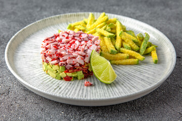 Octopus tartar, avocado and tobiko caviar with deep fried zucchini. Ready menu for the restaurant. Neutral gray blue textured background