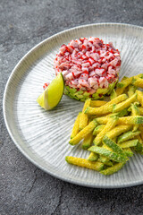 Octopus tartar, avocado and tobiko caviar with deep fried zucchini. Ready menu for the restaurant. Neutral gray blue textured background