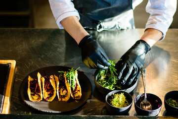 A chef plating tacos in a restaurant kitchen