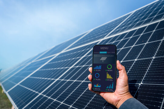 Man hand holding the telephone for monitoring performance in solar power plant(solar cell). Alternative energy to conserve the world's energy, Photovoltaic module idea for clean energy production