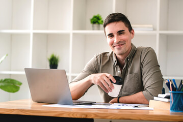 confident young businessman Work from home with laptop and documents on the desk.
