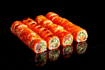 Appetizing california sushi roll set in tobiko caviar with tuna, salmon, eel and avocado on a dark background. Close up, selective focus