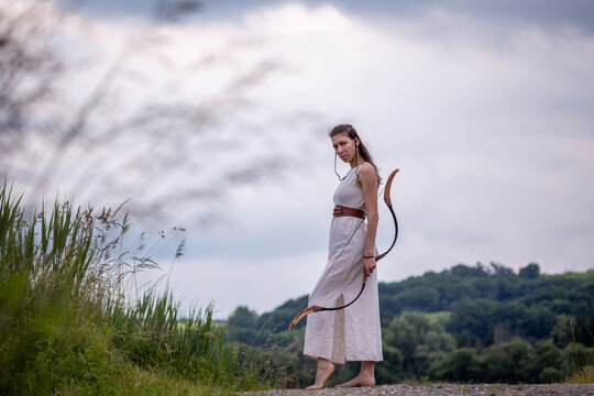 A Hungarian woman in a linen dress with a bow is standing on the road