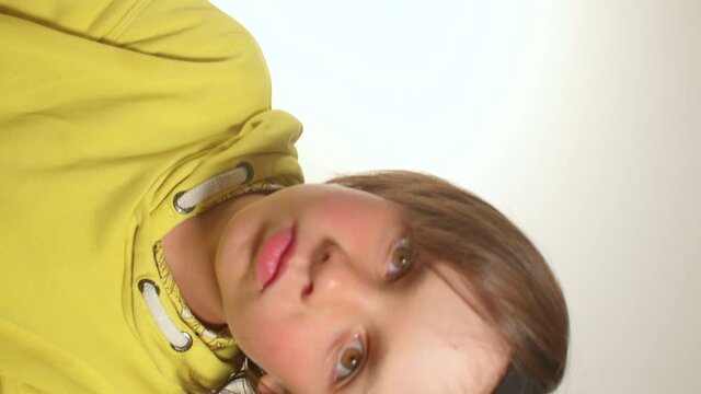 Teenage boy in yellow clothes shakes his hair to the sides. Stops the head, focus of attention to the camera. Motivation for a positive mood. Horizontal video.