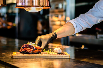 Chef plating barbequed ribs on a counter in a restaurant