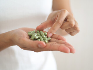 The green pill or andrographis paniculata is on a woman's hand. coronavirus issue and covid-19 prevention concept. closeup photo, blurred.