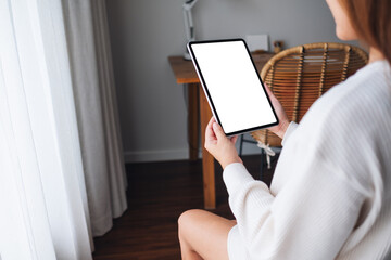 Mockup image of a woman holding digital tablet with blank desktop screen at home