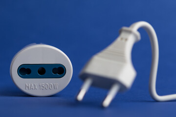 Selective-focus shot of a plug adapter with a cable on a blue surface