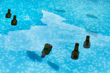 Botellas de cerveza flotando y hundidas dentro de una piscina. Vista de superior