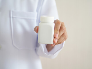 Doctor holding bottle of pills on white background. The concept of healthcare. closeup photo, blurred.