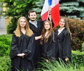group of students graduates of the Faculty of Foreign Languages in robes hold the flag of France in...