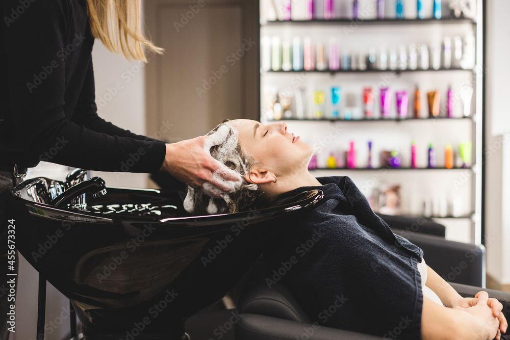 Canvas Prints Master woman hairdresser washes hair of a girl with shampoo before styling in a beauty salon.