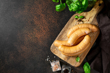 Pork sausages on a serving wooden board on a dark culinary background top view with copyspace