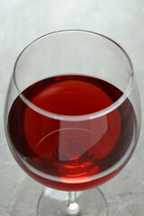 Glass of red wine on gray textured table, close up
