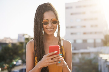 Bohemian african girl using mobile phone outdoor with city in background - Focus on face