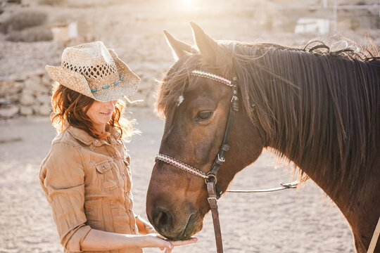 Young farmer woman playing with her bitless horse in a sunny day inside corral ranch - Concept about love between people and animals - Focus on girl face
