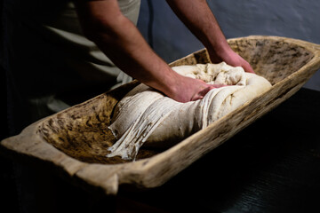 Kneading dough for the oven in a traditional wooden bread trough