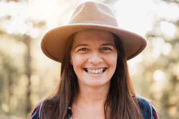 Senior woman smiling on camera outdoor in the woods - Travel concept - Focus on face