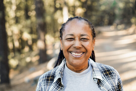 African senior woman smiling on camera outdoor in the woods - Focus on face