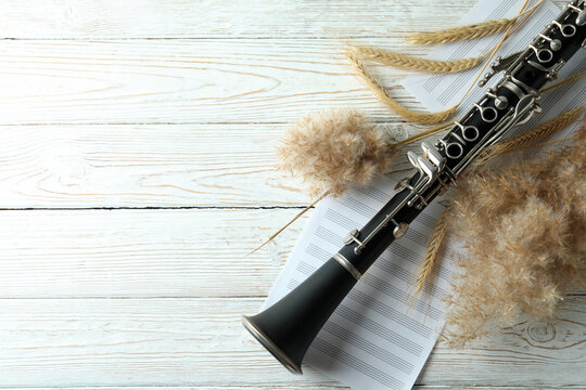 Сlarinet, music sheets and reeds on white wooden table