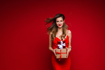beautiful female fashion model in red dress holds a lot of small boxes with presents and rejoices