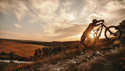 Cyclist with mountain bike at sunset