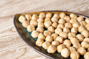 Hazelnuts in selective focus. Nuts on a plate on a white background. Dry hazelnuts. Roasted hazelnuts on a wooden table