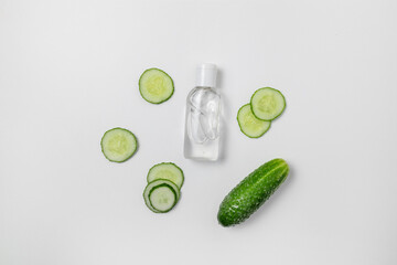 Natural organic cosmetic liquid lotion product with green cucumber slices on white background