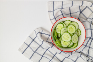 Fresh slice of cucumbers in a bowl with a towel on a gray background. Space for text