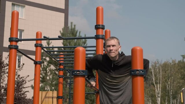 Young Man Exercising on Parallel Bars in an Outdoor Gym. Sport, Fitness, Street Workout and Healthy Lifestyle Concept