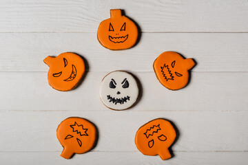 flay lay with homemade and spooky pumpkin shape halloween cookies on white surface