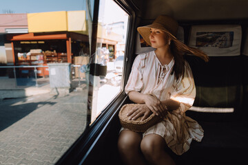 A girl in a hat riding on public transport and looking out the window
