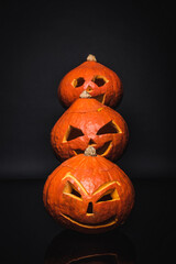 row of creepy and carved pumpkins on black