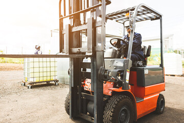 A man on a forklift works in a large warehouse, unloads bags of raw materials
