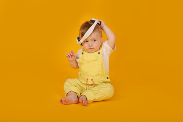 a beautiful blue-eyed little boy in a yellow suit is sitting in white headphones
