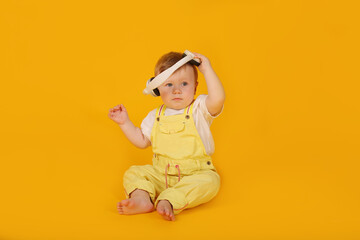 a beautiful blue-eyed little boy in a yellow suit is sitting in white headphones
