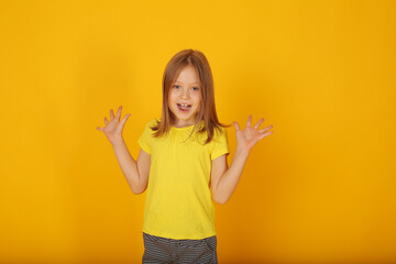 a beautiful brown-haired girl in a yellow T-shirt is surprised by a yellow background