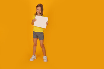 a beautiful brown-haired girl in a yellow T-shirt holds a white sheet of paper with a yellow background