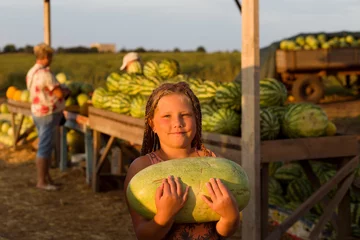 Foto op Canvas Smiling little girl holding big watermelon in steen farmer market. A Lot Of Big Sweet Green Organic Ripe Watermelons In The Farmers Market Healthy Raw Diet Food. © Anna