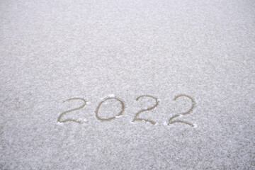 Number 2022 are written in the snow on white background, copy space