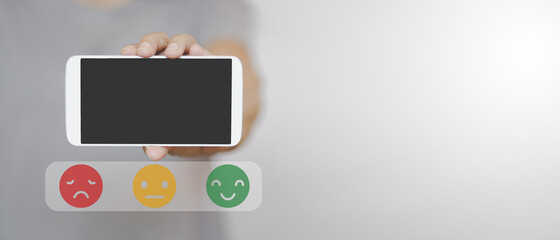 hand holding white smartphone with clipping path on touchscreen and mental emoticon in soft focus,  for feedback, rating, ranking, customer review for service or product concept