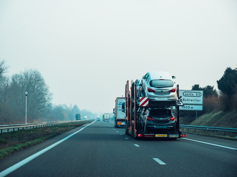 France - FEb 8, 2018: Rear view of long cargo truck carrying on the highway multiple Opel cars near the Rohrwiller village - vinter conditions on the highway