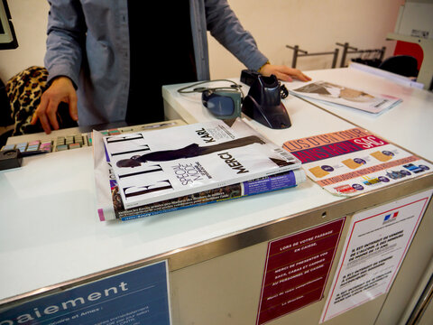 PAris, France - Feb 23, 2019: Low Angle View Of Press Kiosk With Woman Seller And Elle Fashion Magazine With Headline Thank You Karl Lagerfeld