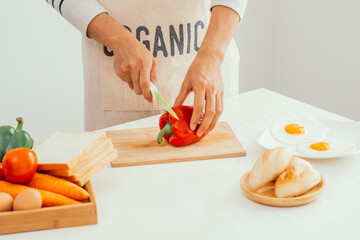 Obraz na płótnie Canvas Male hands slicing red bell pepper on wooden cutting board