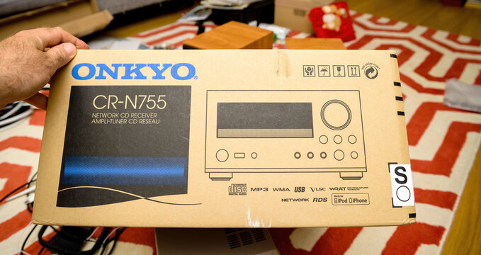 Paris, France - Jun 14, 2021: POV male hand holding new package for mini hi-fi component audi system by Onkyo CR-N755 network cd receiver with Compact Disc logotype, mp3, wma, usb, vls
