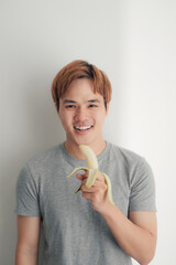 An asian with a beautiful face eats a banana and smiles