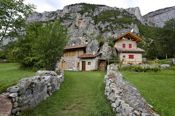 Fototapeta na wymiar Cottage wedged between rocks on a plateau in the Trentino Alps, Italy.
