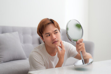 Frustrated handsome millennial guy concerned about facial skin problem