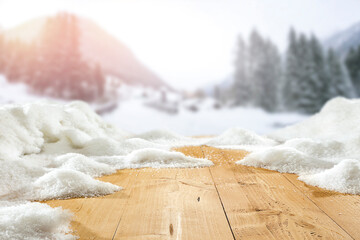 Fresh white snow on a wooden table against the backdrop of a bright mountain landscape on a beautiful winter day 